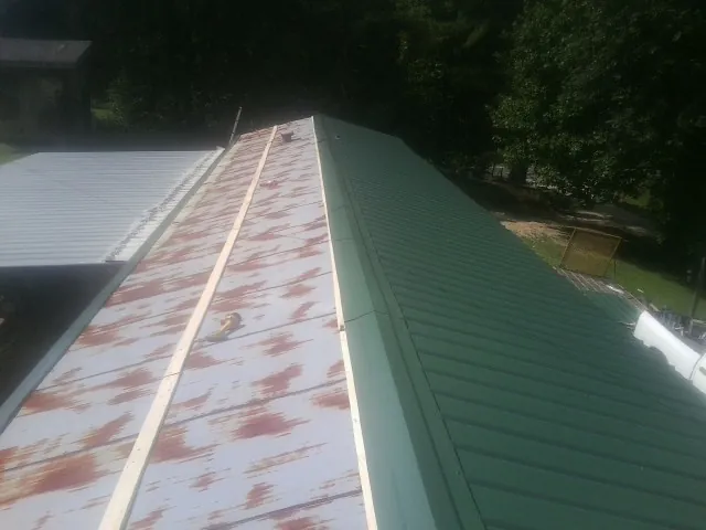 Old rusted panels beside newly installed green metal roofing — Wind Damage Roof Repair by Roofing Brothers in Milton