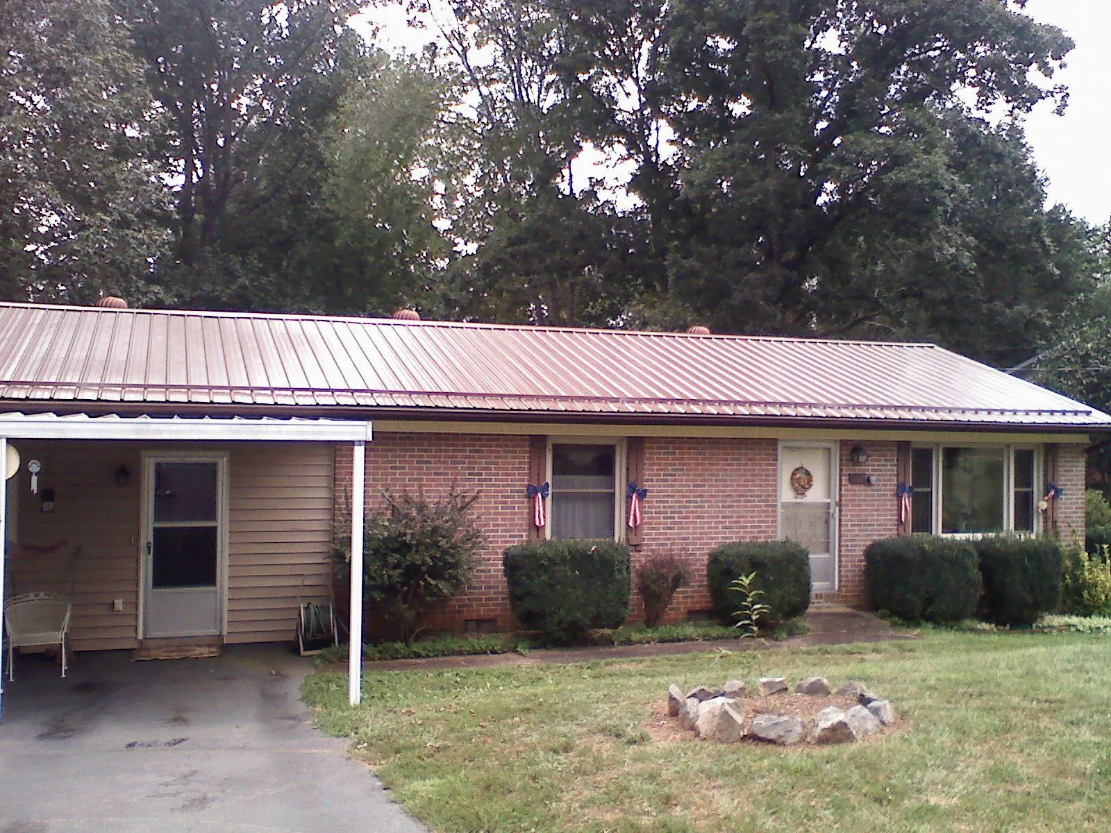 Bronze metal roof and carport on a brick ranch home — Roof Repair work by our crew in Milton